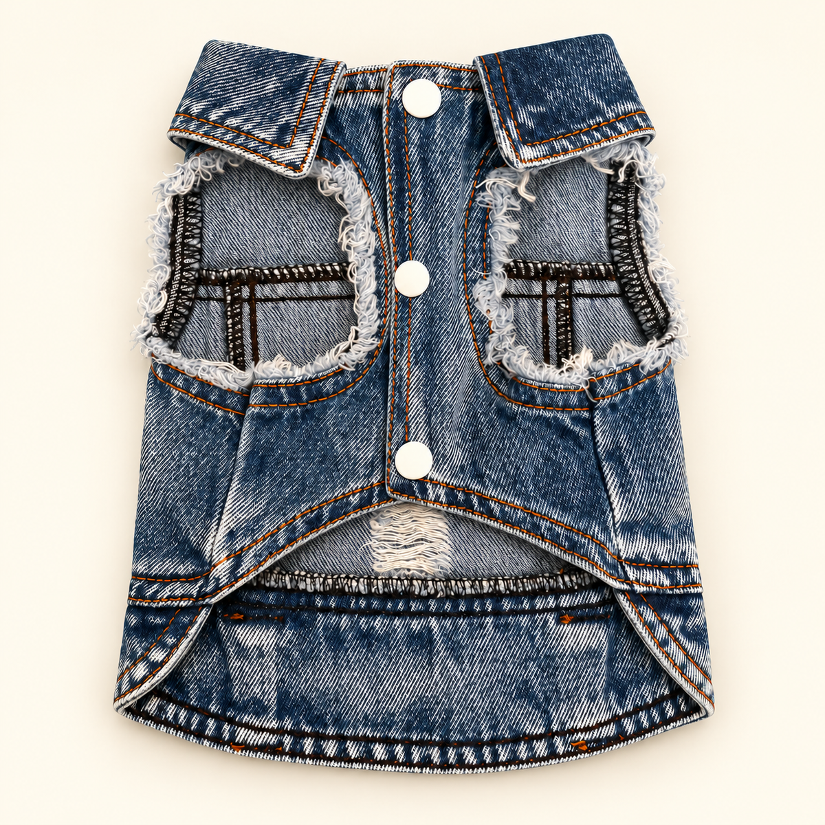 A dog vest made from blue denim jeans, styled with white buttons, frayed edges, and distressed details, laid flat on a light cream background.