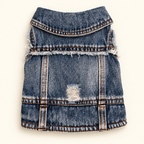 A blue denim vest for small pets, featuring a distressed ripped detail on the front and frayed edges, shown flat against a light cream background.