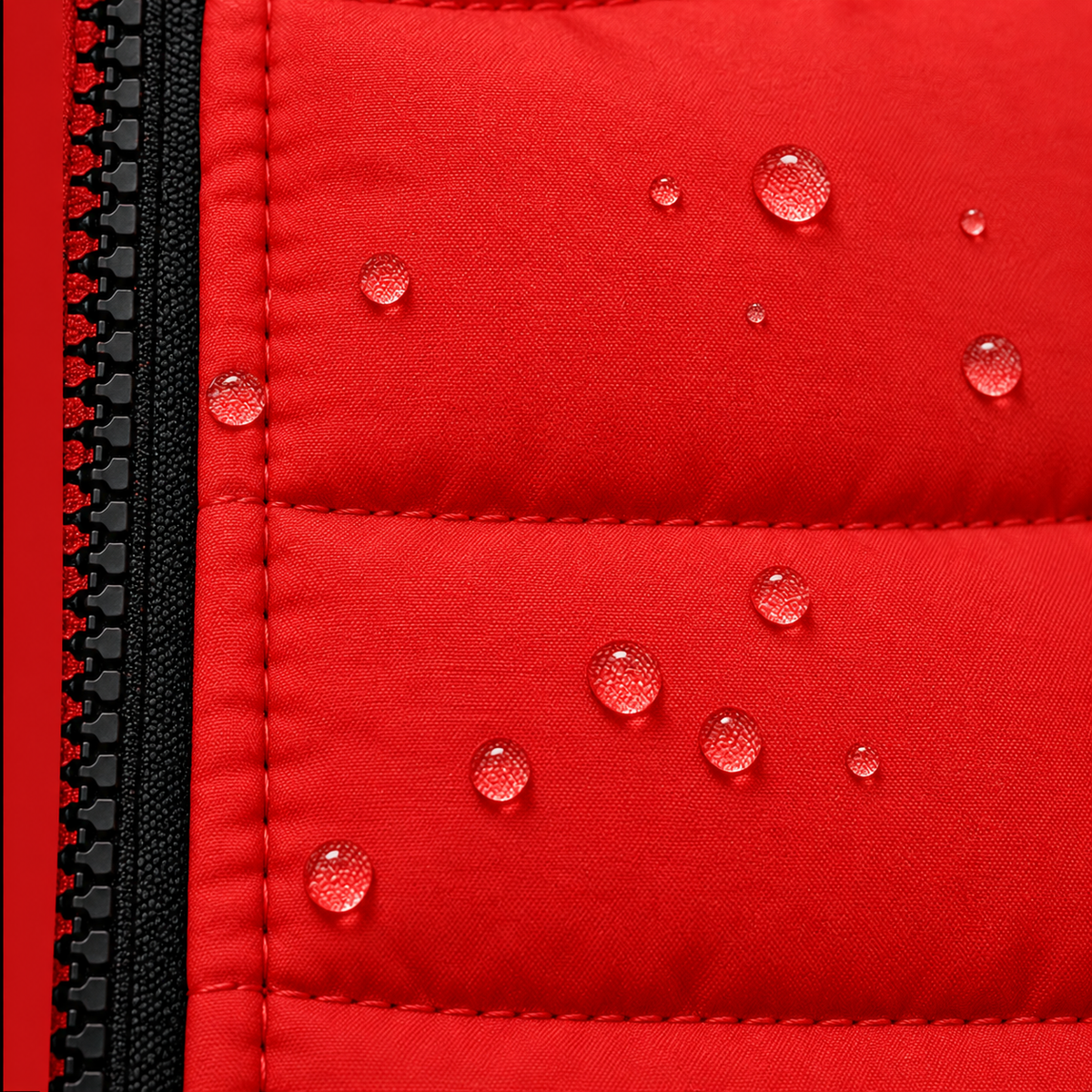 Close-up of a bright red quilted fabric surface with water droplets beaded along the zipper edge, showing water repellency.