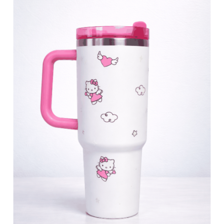 White travel mug with pink handle and Hello Kitty designs on a white background