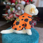 Side view of small dog wearing orange Cheetos Dog Hoodie with black polka dots outdoors