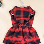 Close-up of red plaid dog dress showing festive tartan fabric detail and black bow accent