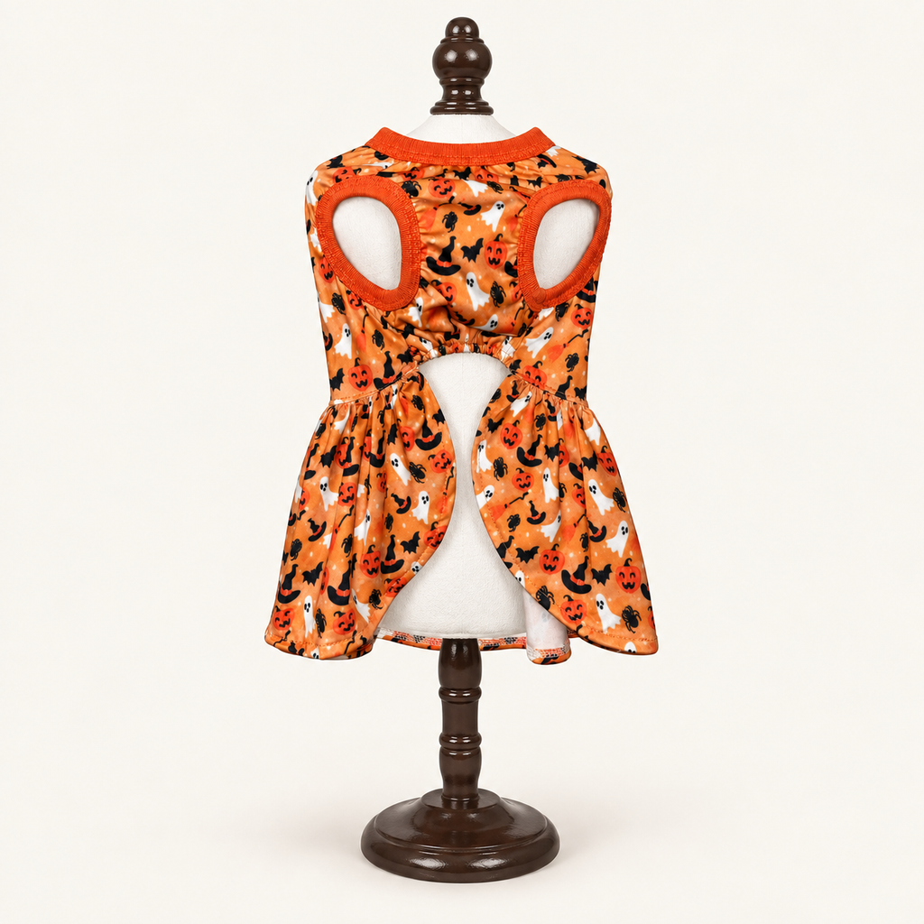 Rear view of the orange Halloween dog dress with black and white pumpkin print, displayed on a mannequin torso on a wooden stand