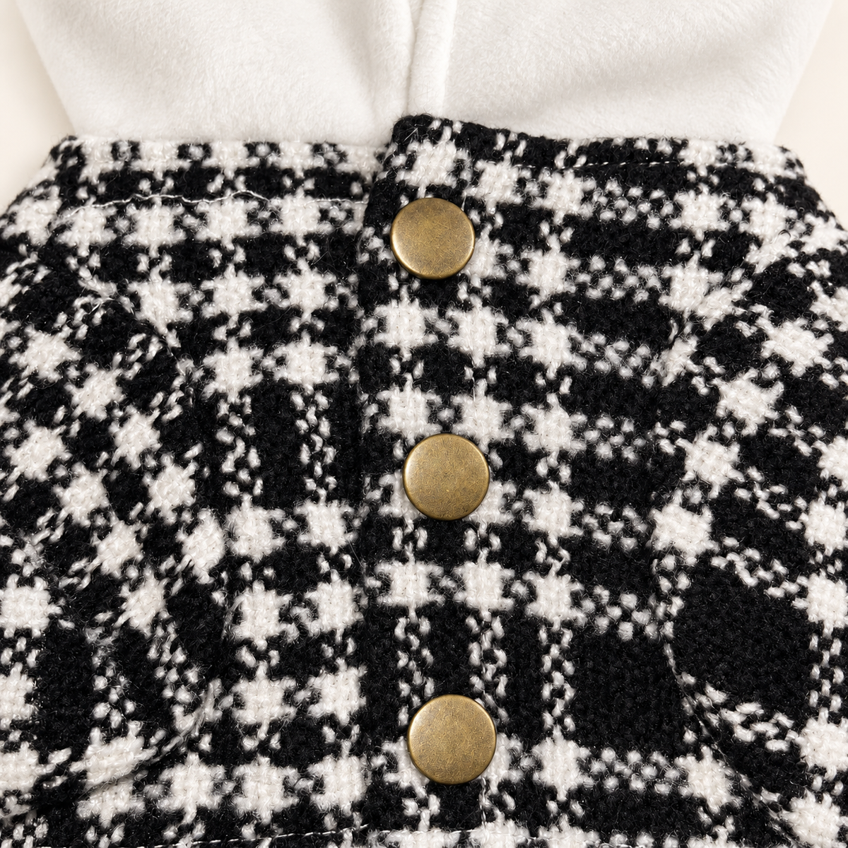 Close-up of three antique brass buttons and houndstooth tweed construction