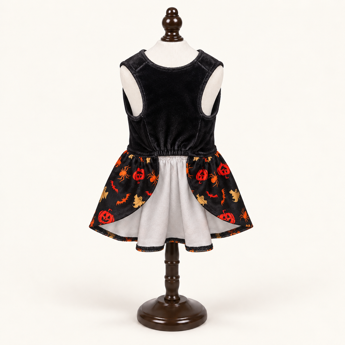Front underside view of the Happy Halloween Bow dog dress on an espresso catalog stand