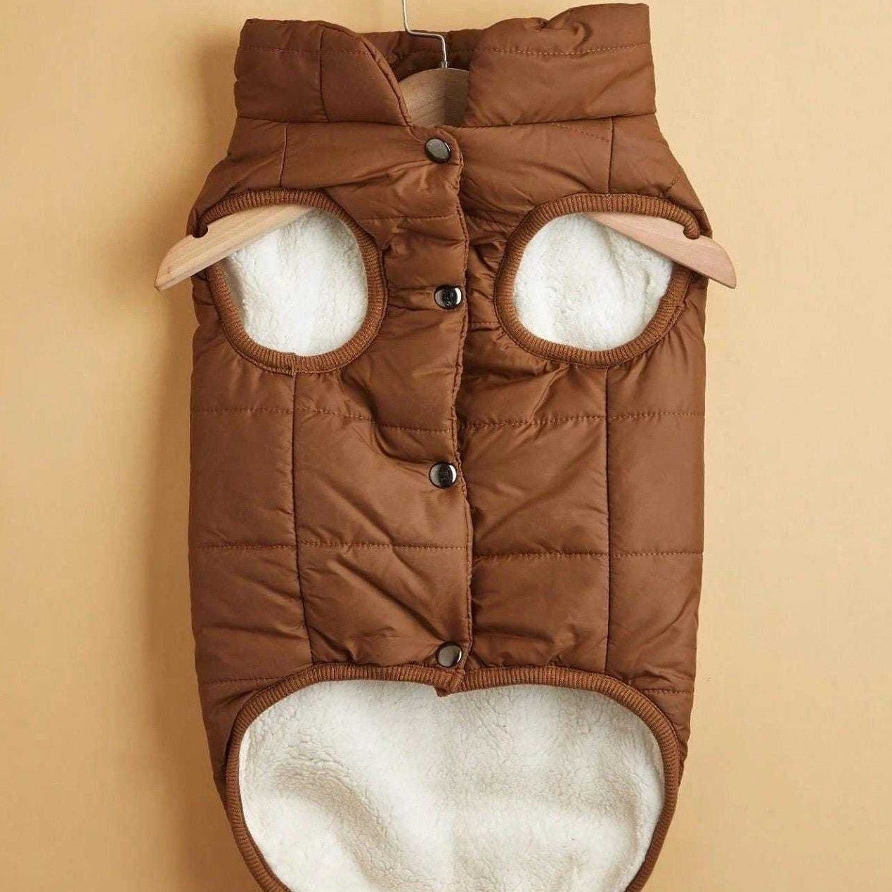 Close-up of brown quilted dog jacket snap button closure