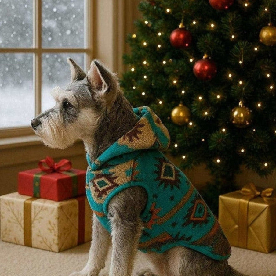 Small dog wearing turquoise and brown Aztec Fleece Dog Hoodie next to decorated Christmas tree and wrapped gifts