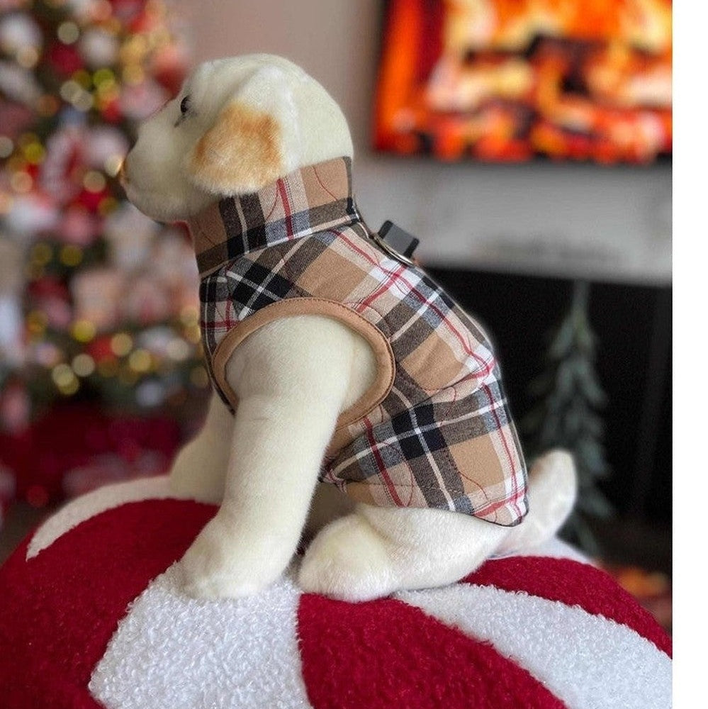 Stuffed dog toy wearing a plaid coat on a red and white striped cushion with a Christmas tree and TV in the background.