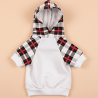 White dog hoodie with red black plaid sleeves on soft peach pastel background